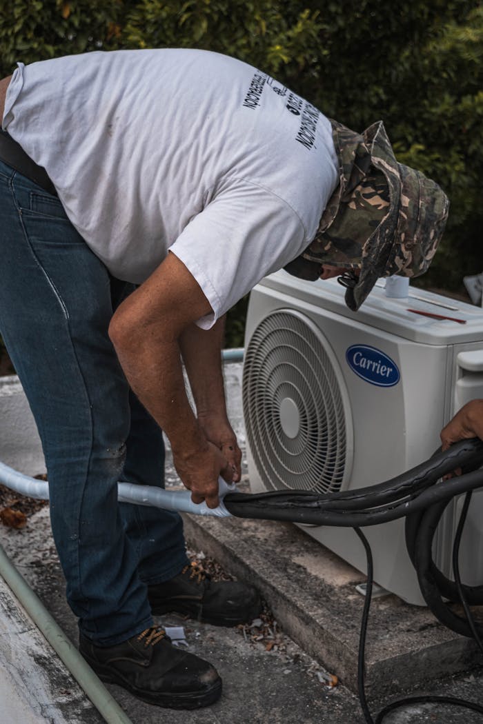 The Art of Drawing Readers In: Your attractive post title goes here A technician performs maintenance on an outdoor air conditioning unit, focusing on hose connections.